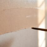 Manos pintan una pared artística cálida