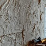 Un albañil confuso examina una pared imperfecta